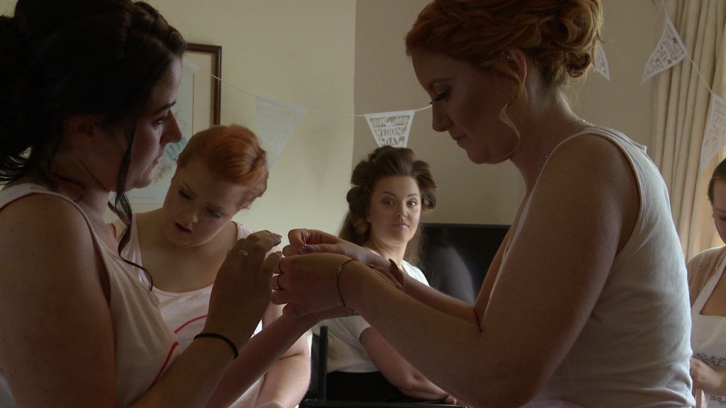 th bride looks on as her bridesmaids fasten their bracelets and get ready for the wedding at thornton Manor in the wirral