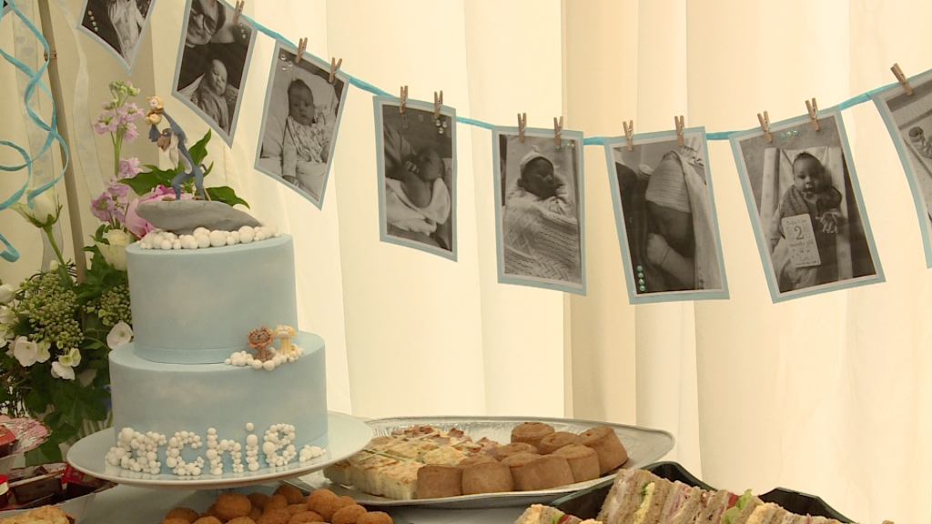 a blue homemade christening cake lion king theme sits on the buffet table with milestone baby boy bunting