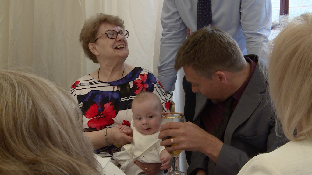 family enjoy having a cuddle with the christening boy and someone jokingly holds a pint near him in Warrington