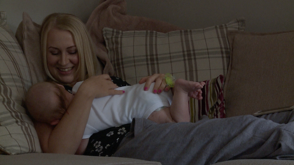 a mum enjoys a sleepy cuddle on her sofa at her home in Appleton before his christening