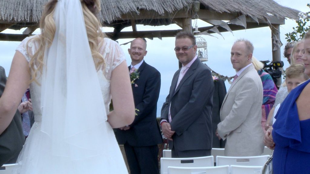 the groom sees his bride for the first time and grins as she walks down the aisle at their outdoor ceremony at abels harp