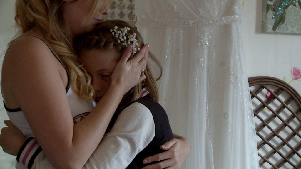 a bride mum hugs her daughter close as they have an emotional moment on the wedding video after talking about missing her Mum