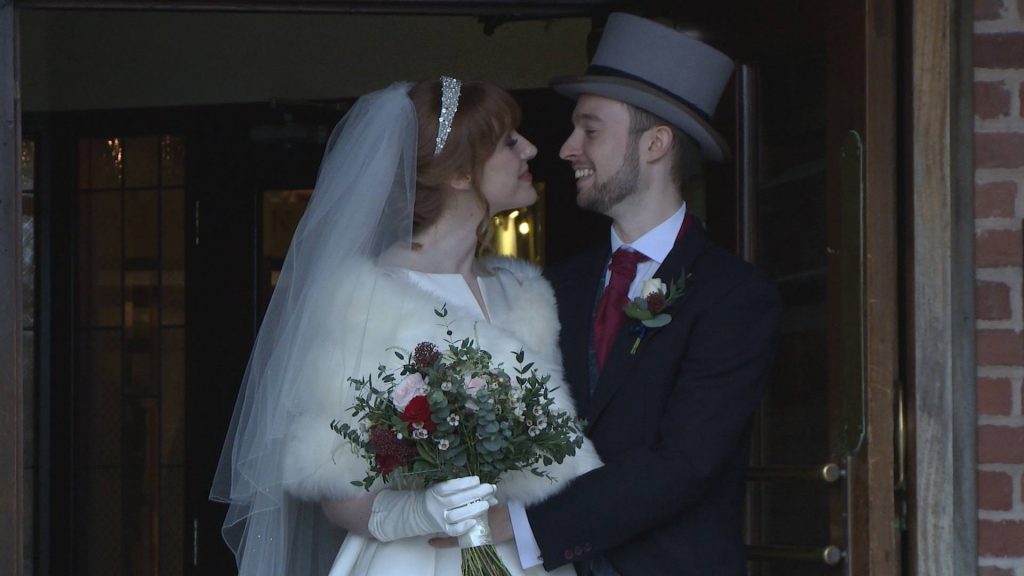 a mid shot of the bride and groom smiling at each other as they hide from the rain on their wedding day at The Villa at wrea green near preston
