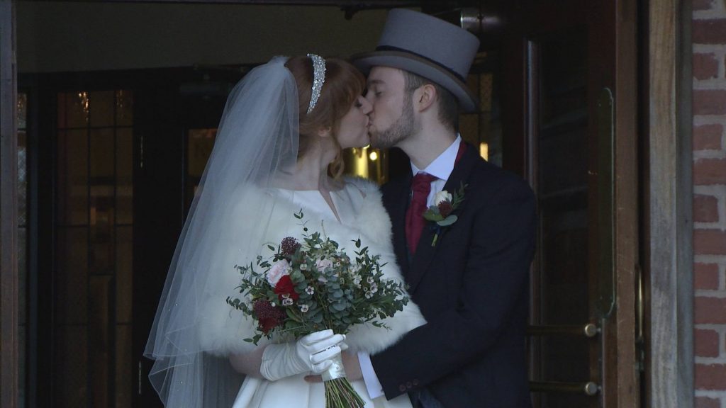 an elegant Parisienne style bride with long white gloves and a faux fur shrug poses with her groom wearing a top hat outside the villa at wrea green near preston