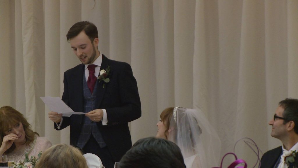 the groom stands to make his wedding speech and we can see the mother of the bride wiping a tear away from her eye during a wedding reception at the villa wrea green