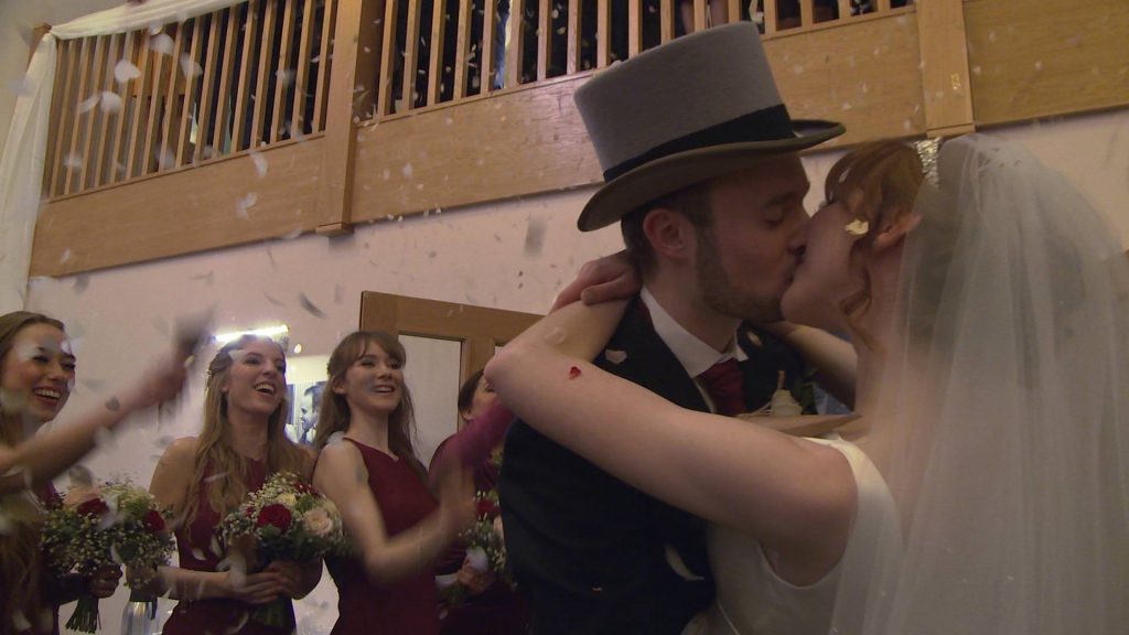 a bride and groom kiss during an indoor confetti photography moment with natural rose petals