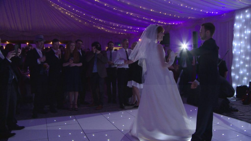 a video still of the bride and groom having their first dance at their evening reception at the villa at wrea green inside the marquee