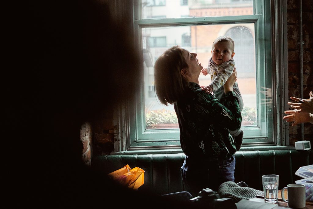a mum holds her baby boy up during a family photography workshop in Manchester. Moment captured for a behind the scenes video