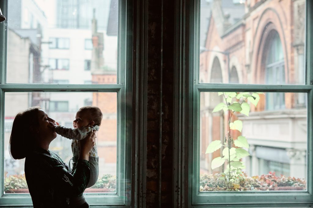 a mum stands in front of a large window in Trof Manchester for The Roost family photography workshop