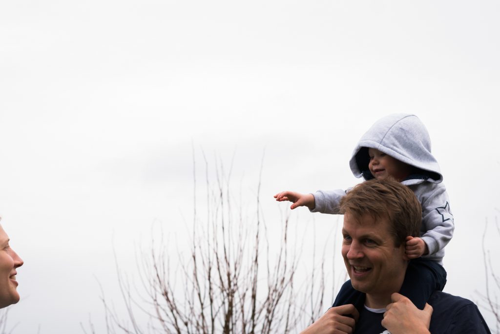 a little girl sits on her dads shoulders during an outdoor family shoot