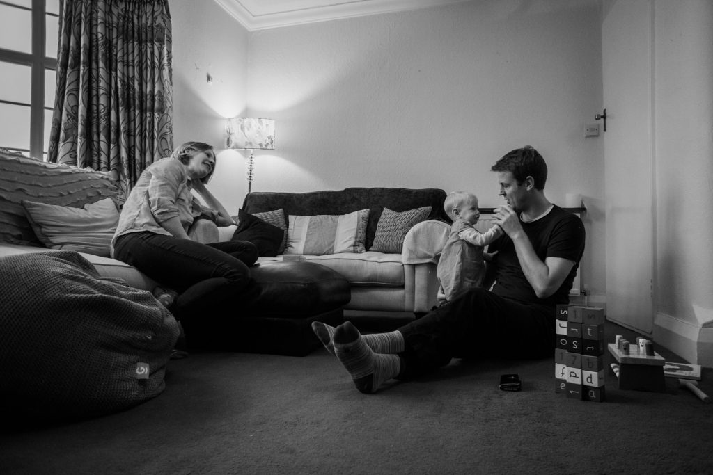 a black and white documentary style relaxed family photo in the living room as they play together during a family shoot in Hale
