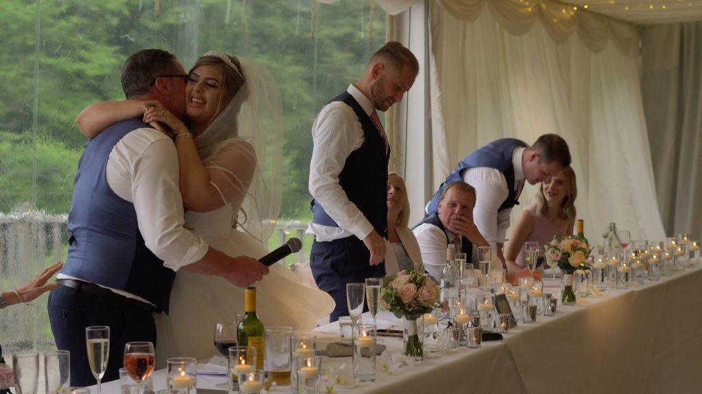 a bride hugs her dad after his speech at a lakeside wedding in the wirral