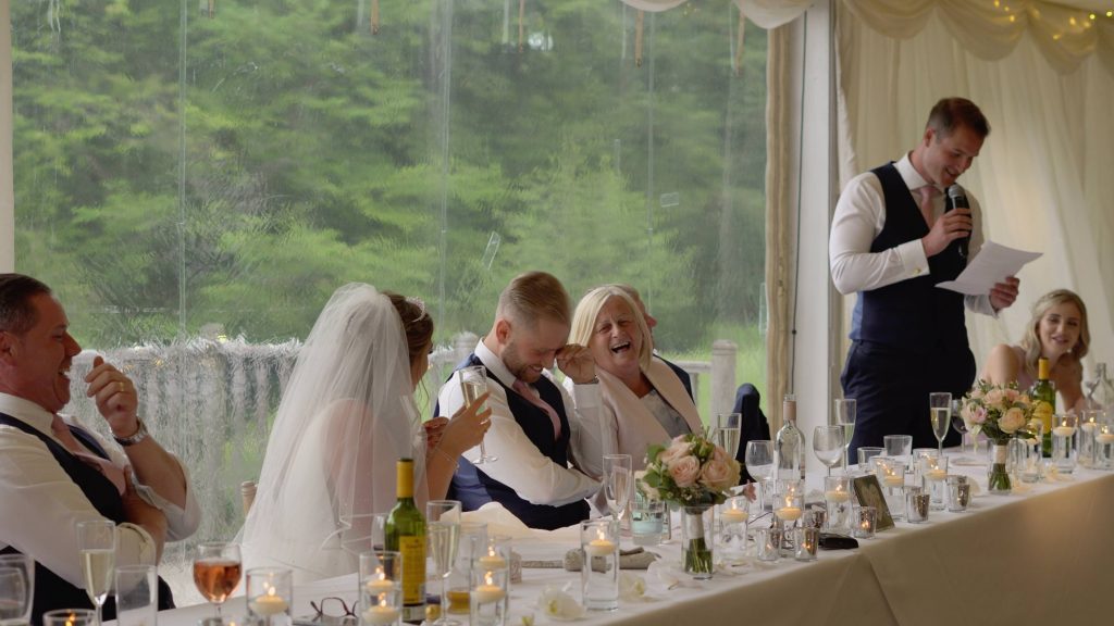 a still from the wedding video of the groom looking embarrassed during the best mans speech at lakeside thornton manor