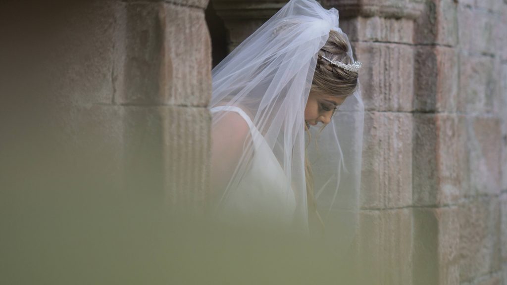 a close up shot of a bride looking down and her wedding veil around her shoulders posing for photos at thornton manor