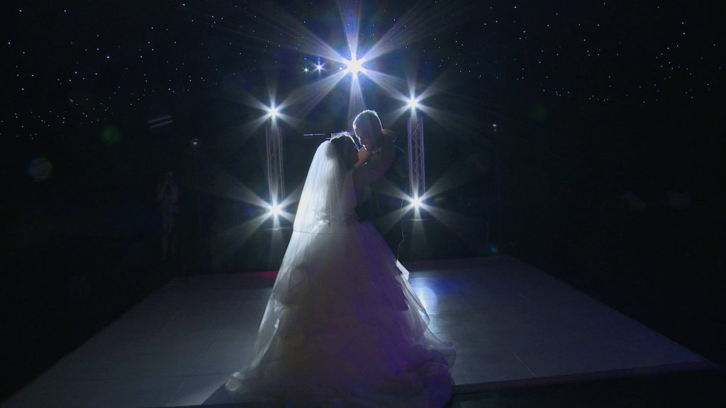 the bride and groom have a surprise curtain reveal for their first dance at a wedding reception at lakeside marquee in the wirral