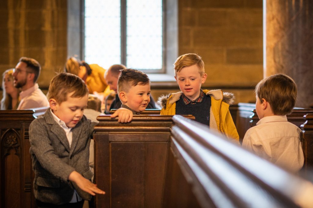 a documentary photograph of a group of 4 young boys playing around inside the unitarian church in Todmorden before a family humanist blessing