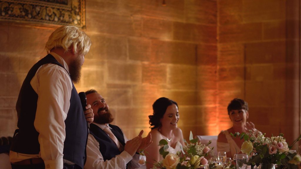 the bride and groom laugh during the fun best mans speech during their wedding reception at peckforton castle in cheshire