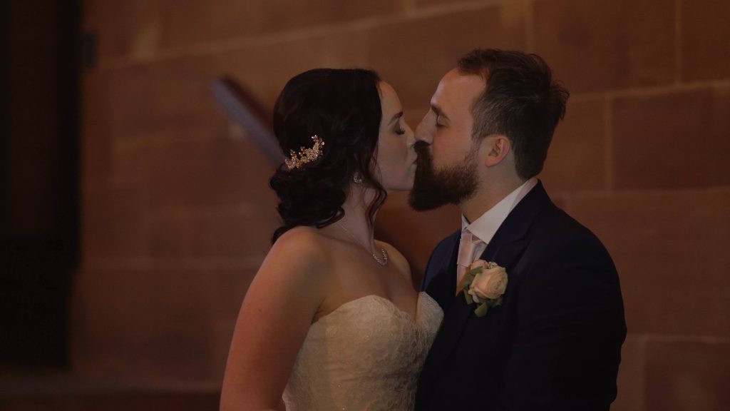 lisa and ste the bride and groom enjoy a romantic kiss on the spiral stairs inside Peckforton Castle