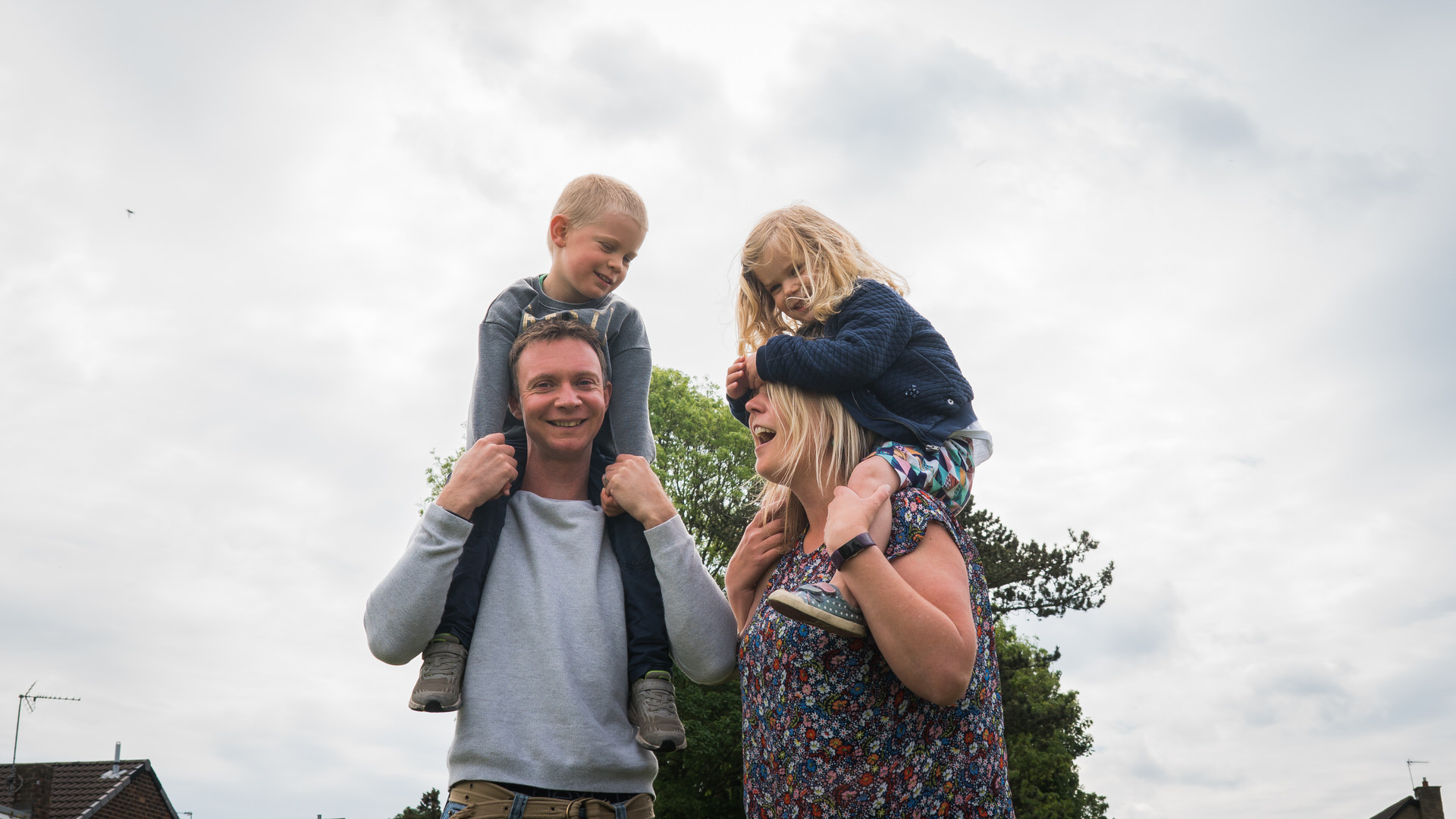 an alternative family portrait of a family being silly with the kids on shoulders at the park