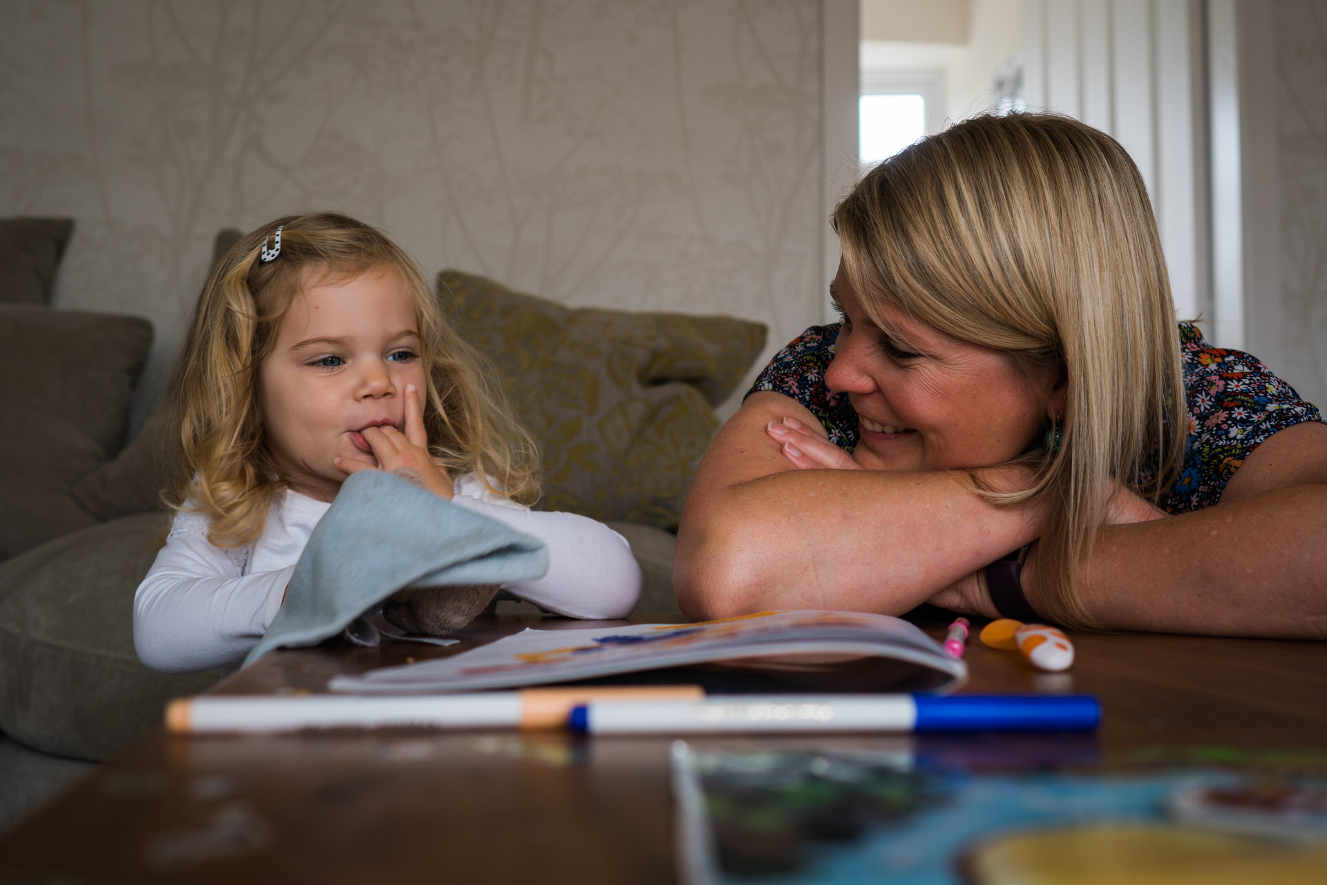 a mum leans on her arms and smiles at her daughter during their home family photo shoot in Wetherby