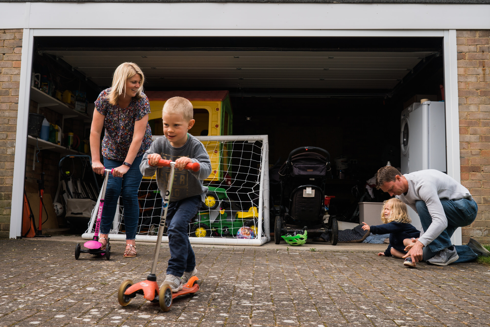 reportage style photograph of a family racing on scooters outside their home yorkshire