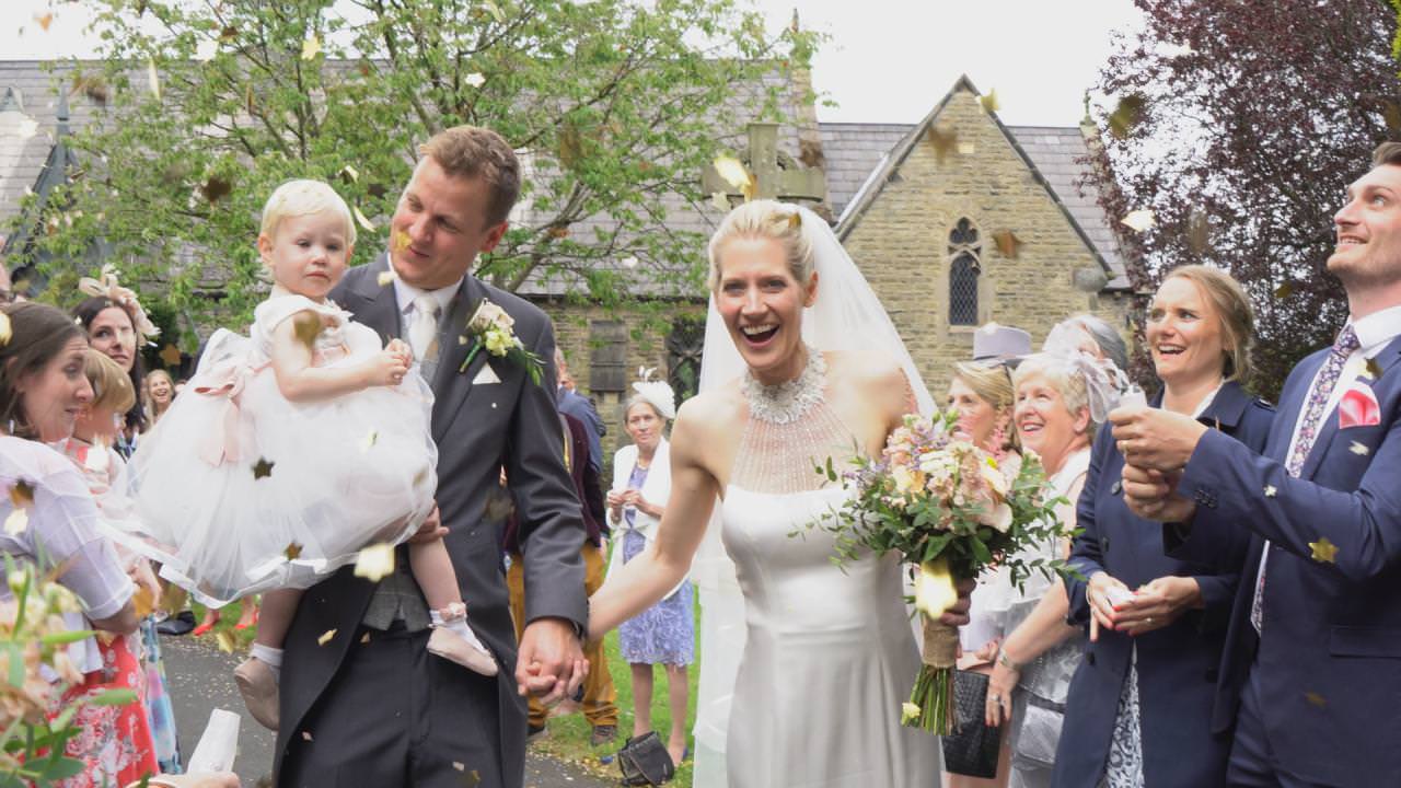 video still of a bride and groom outside St Marks Church covered in confetti