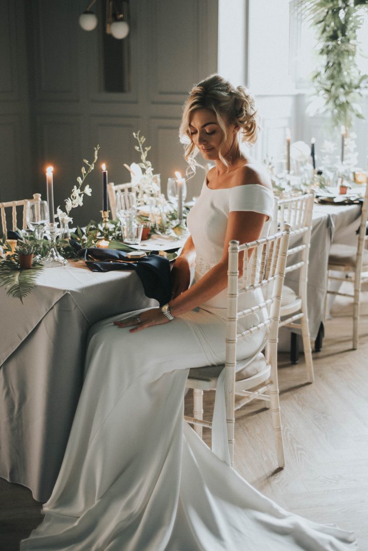a bride sits down looking at her bouquet at the library inside Albert's Standish