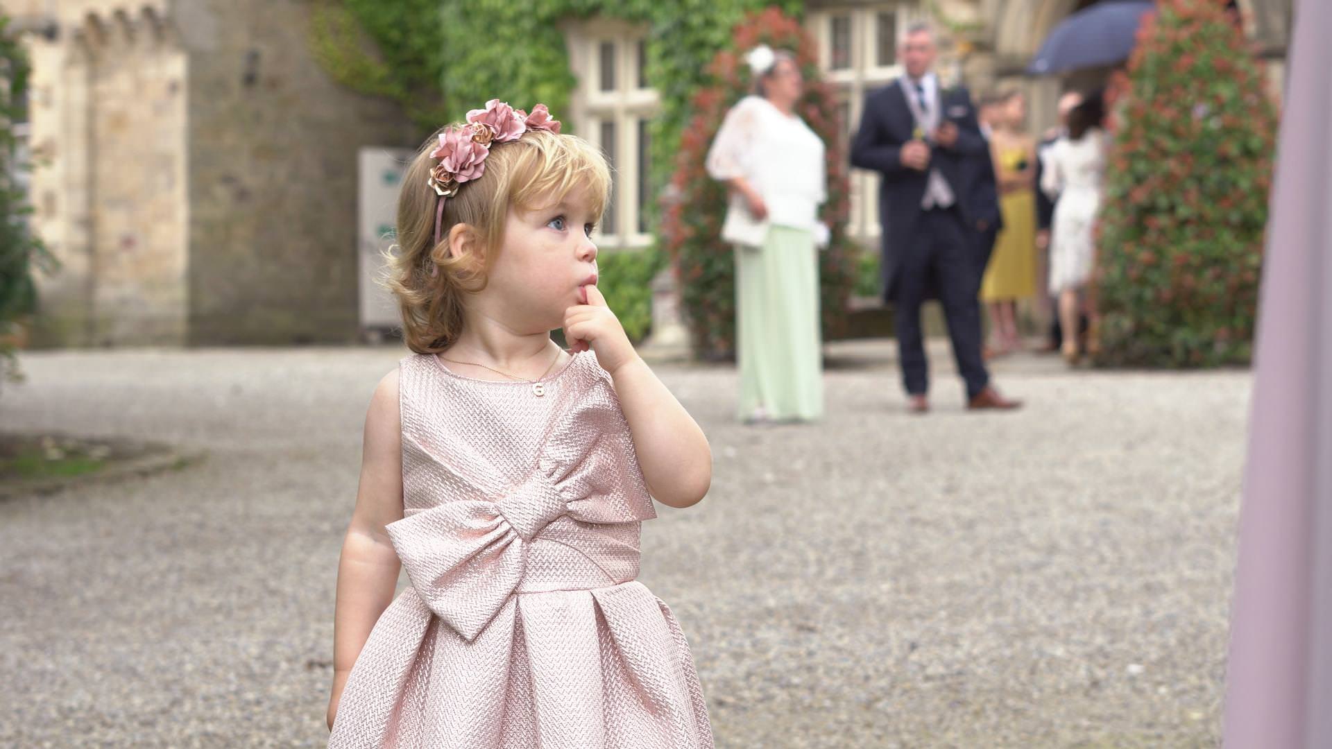 a cute little girl with a flower crown looks on at a wedding at Mitton Hall