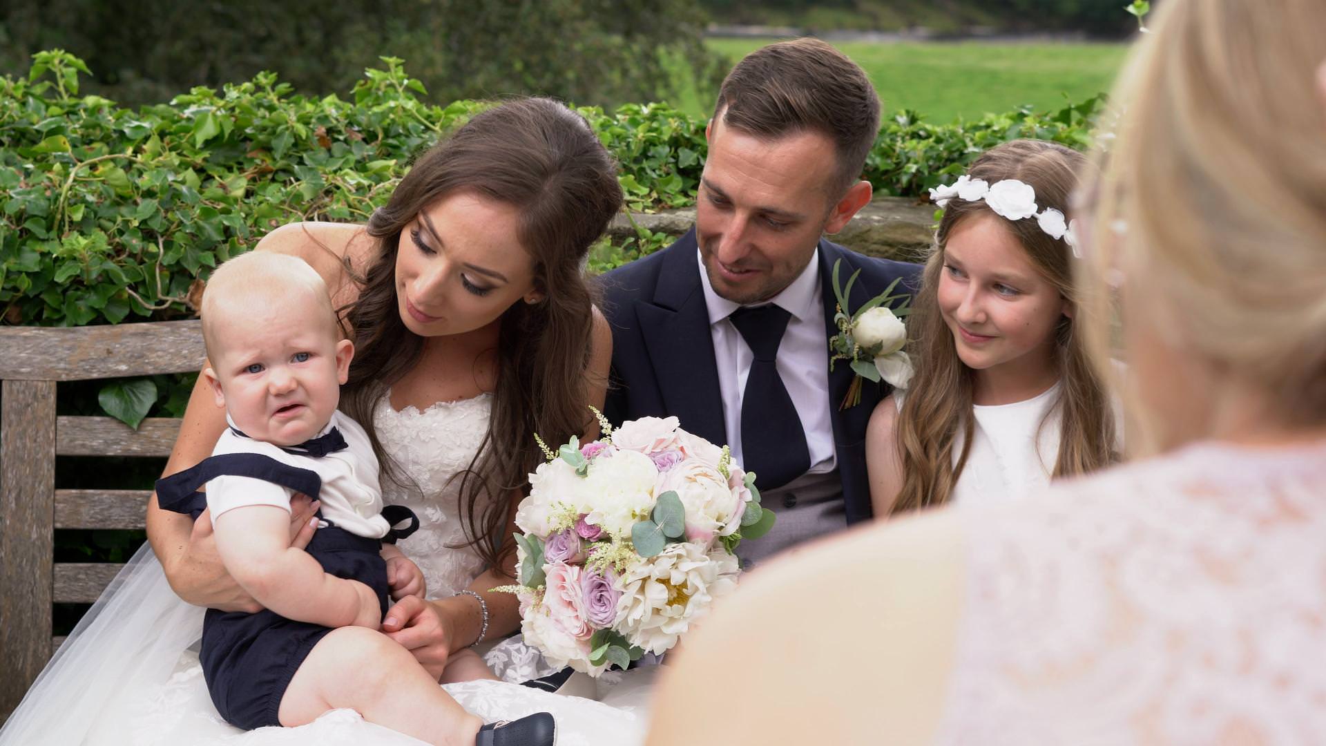 a baby boy doesn't look impressed being made to pose for wedding photos at Mitton Hall in Lancashire
