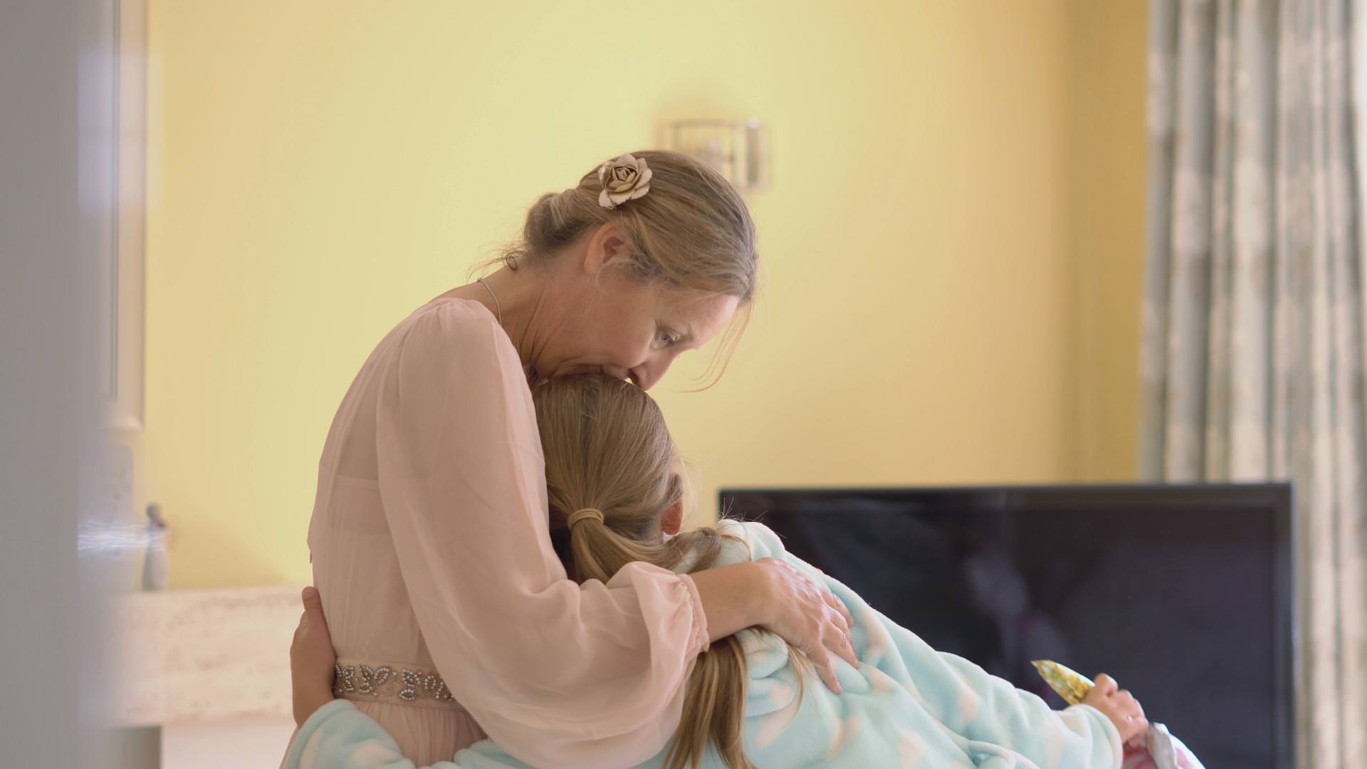 a mum kisses her daughter on the head during a wedding morning