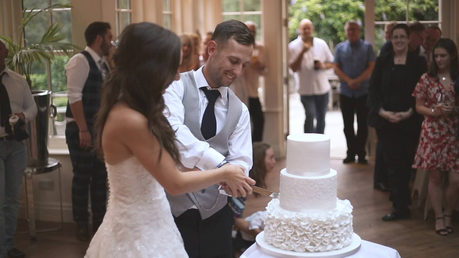 a bride and groom cut their white wedding cake at mitton hall in Lancashire