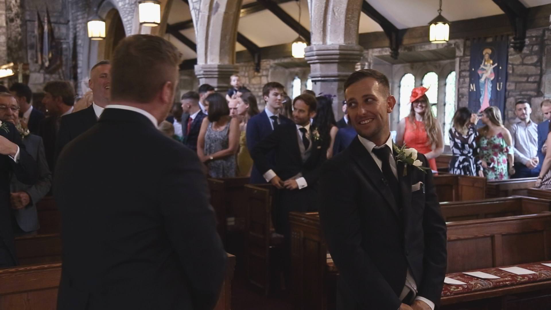 a groom smiles at his best man before a wedding ceremony at St Bartholomews and St John’s Church in Great Harwood