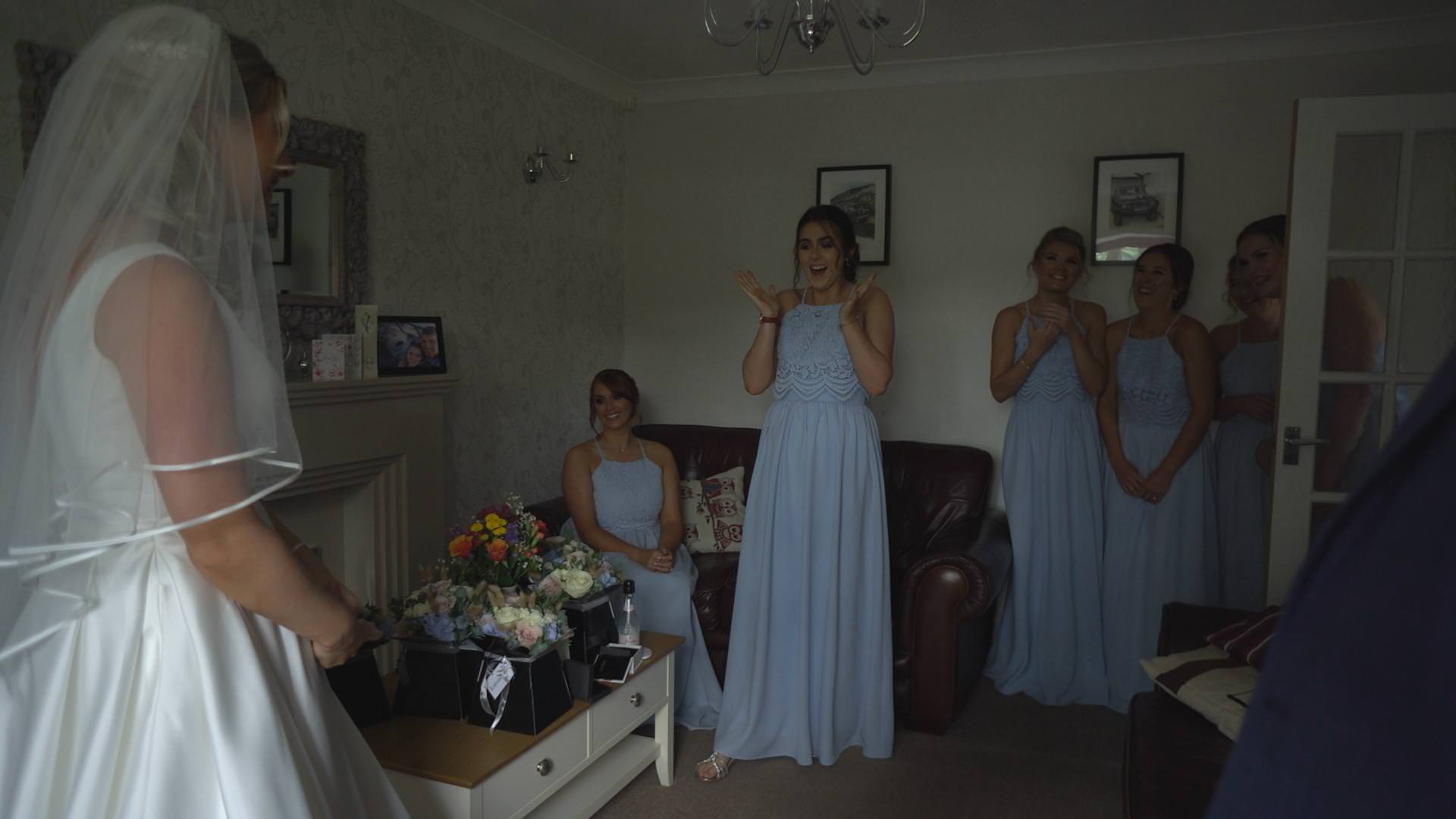 bridesmaids wearing baby blue dresses react to seeing the bride for the first time