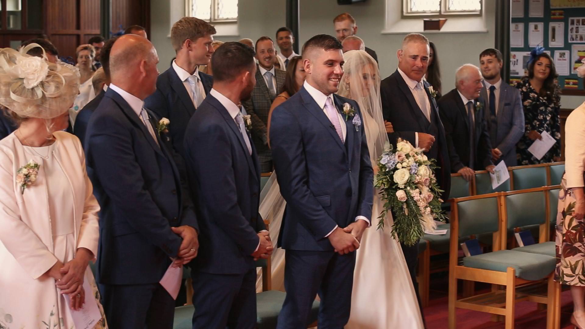 a groom looks happy as his bride walks down the aisle at St Johns in Burscough