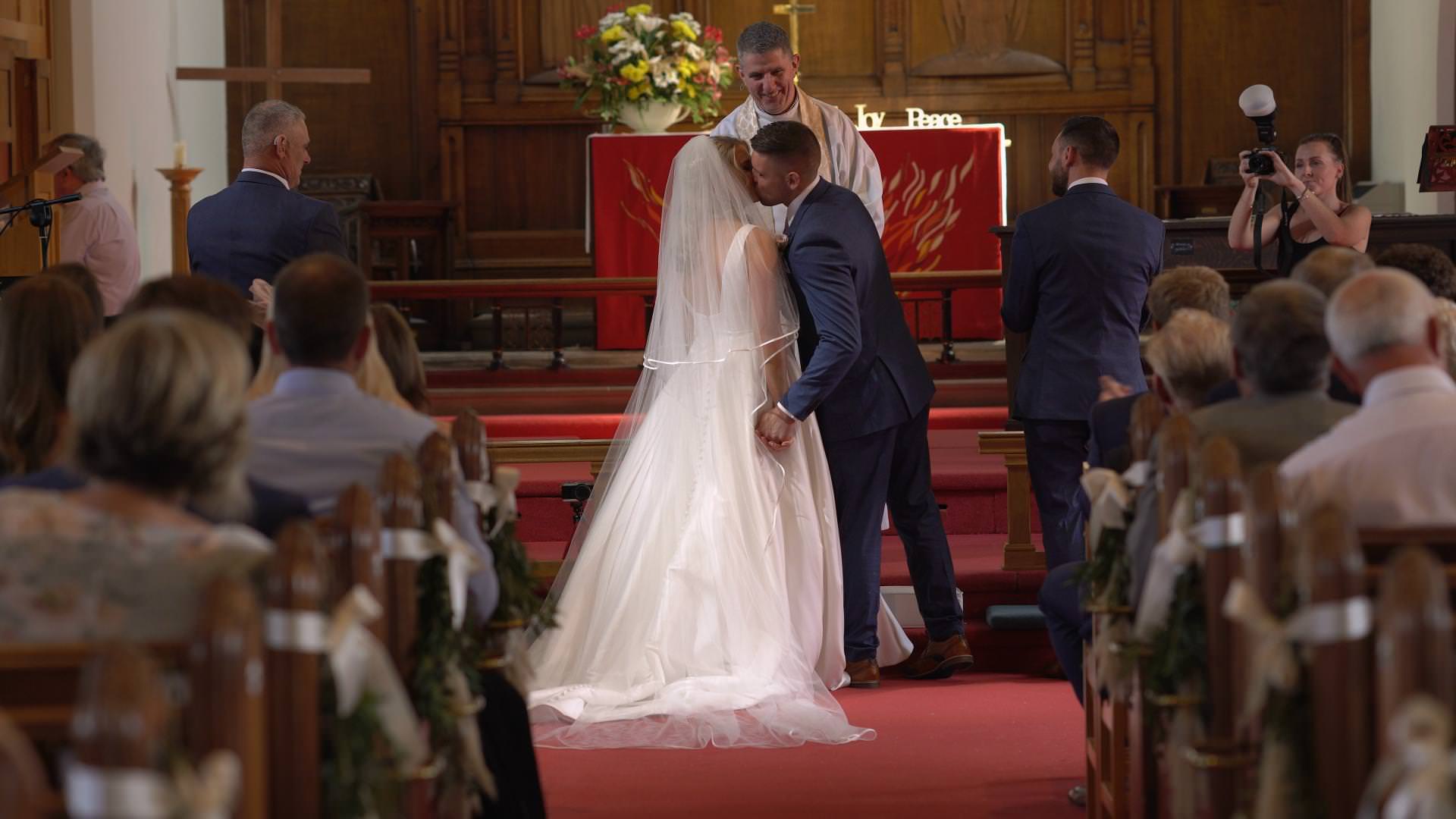 a bride and groom kiss at st johns church in burscough lancashire