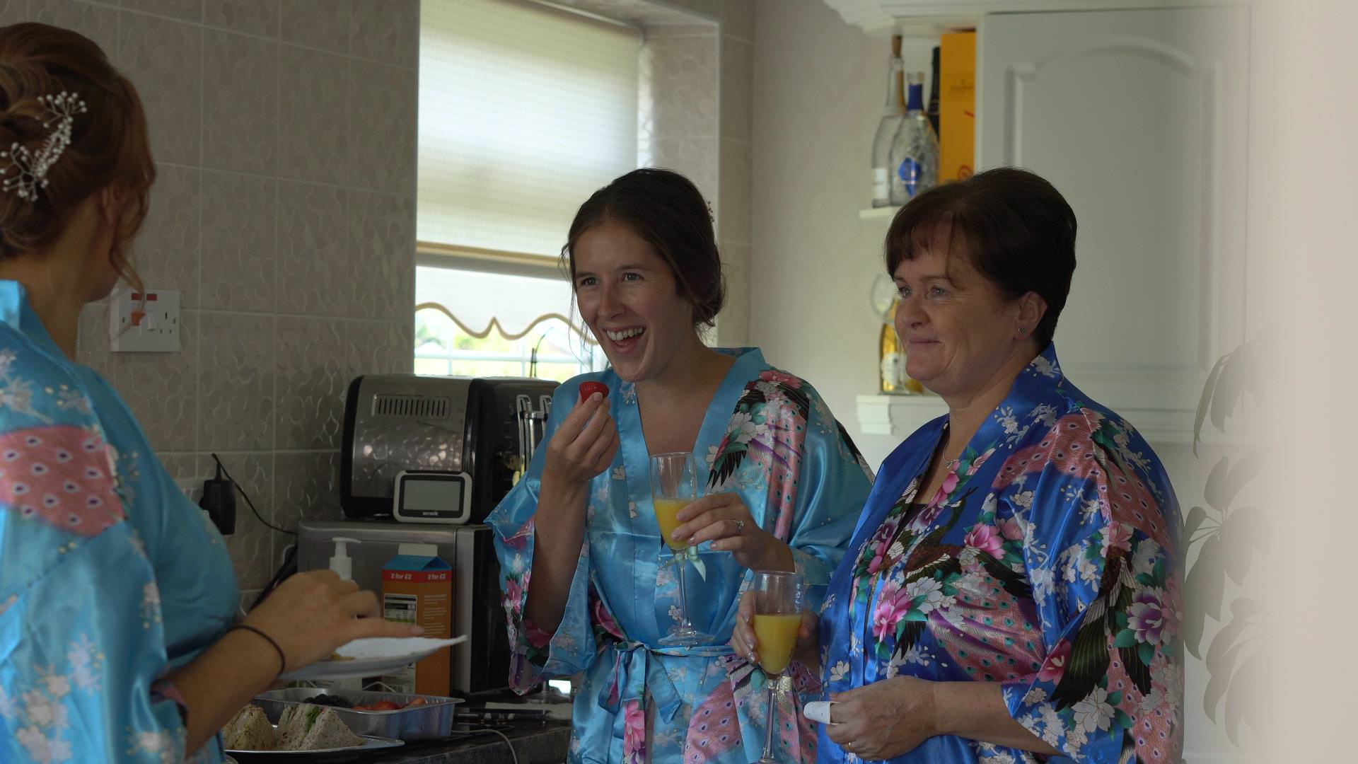 wedding video still of bridesmaids and mum laughing in matching silk kimono dressing gowns