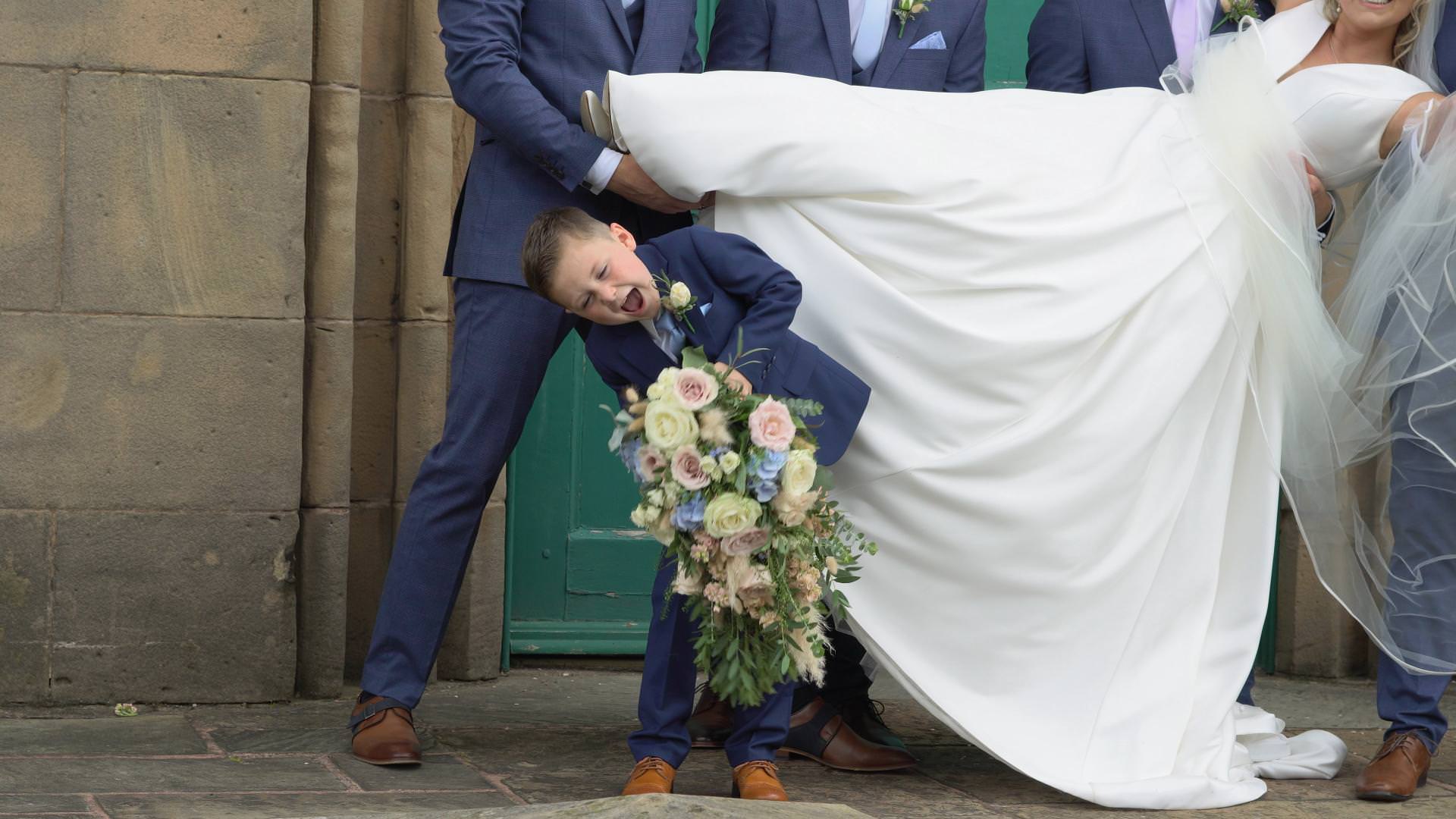 a page boy struggles to hold a heavy bridal bouquet in Lancashire