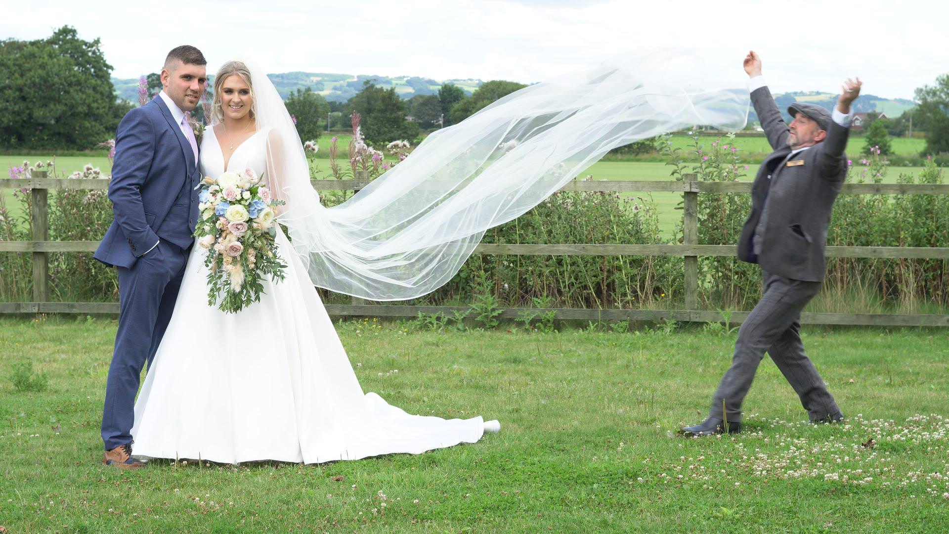 a driver from Grace wedding cars helps with the veil during wedding photos in Burscough