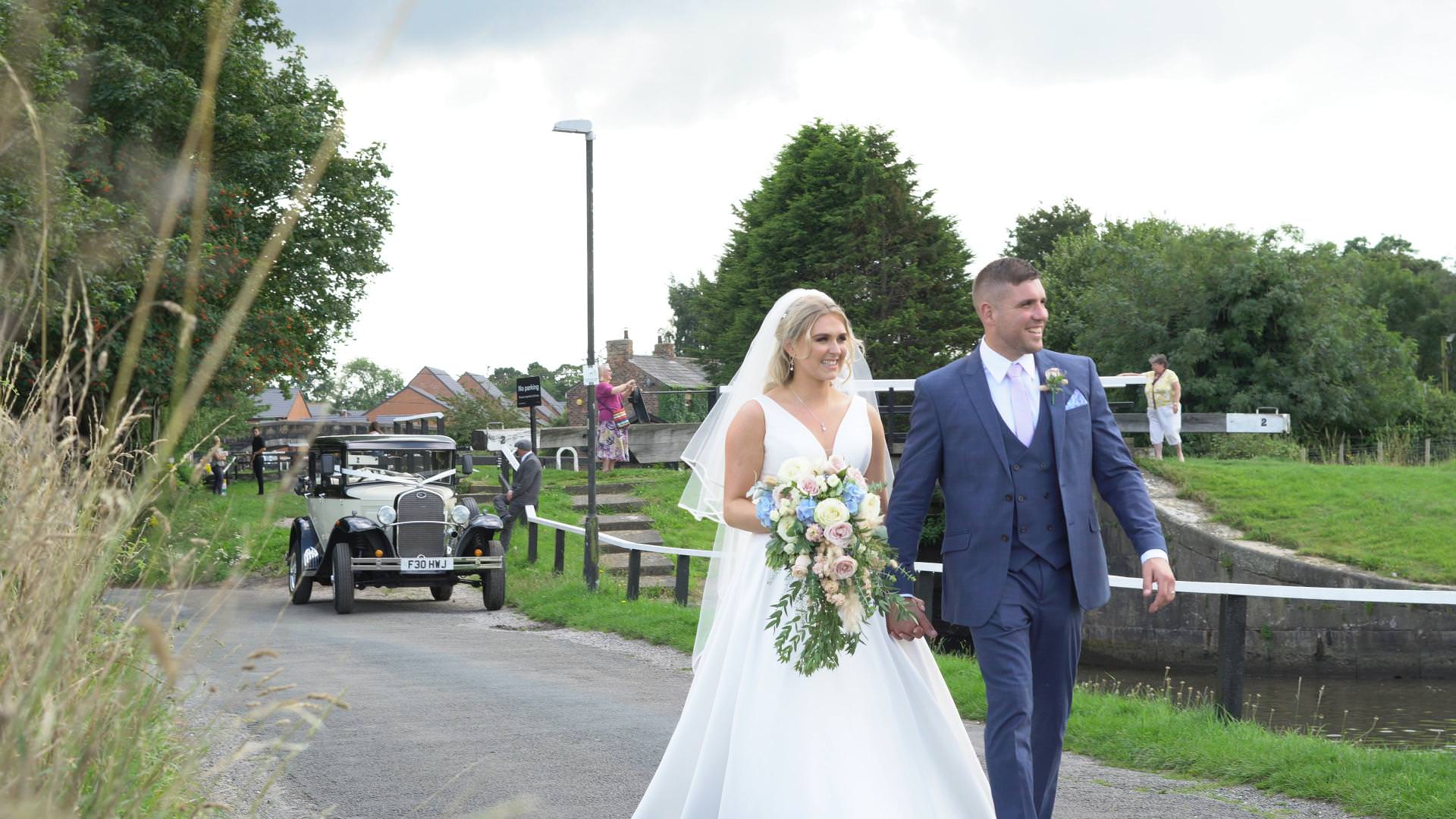 a bride and groom walk beside the leeds liverpool canal in Burscough during their wedding day