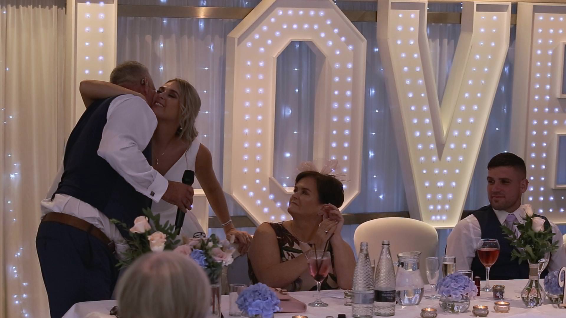 a video still of a bride kissing her dad after his emotional wedding speech at Briars Hall