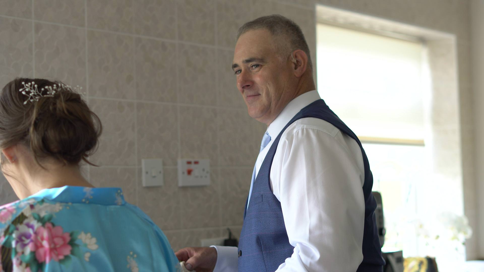 a dad in his wedding suit smiles at his daughter