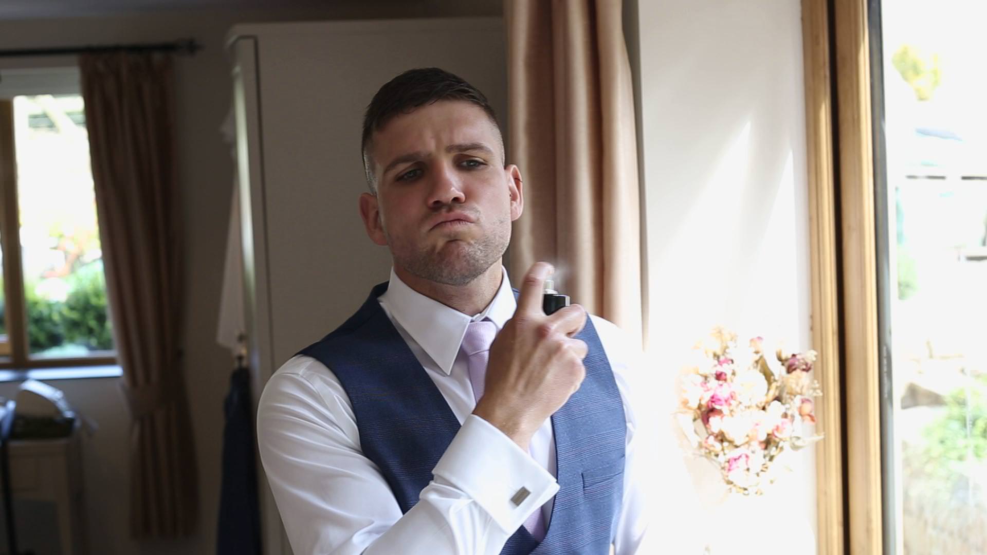 wedding video still of a groom spraying aftershave in Newburgh