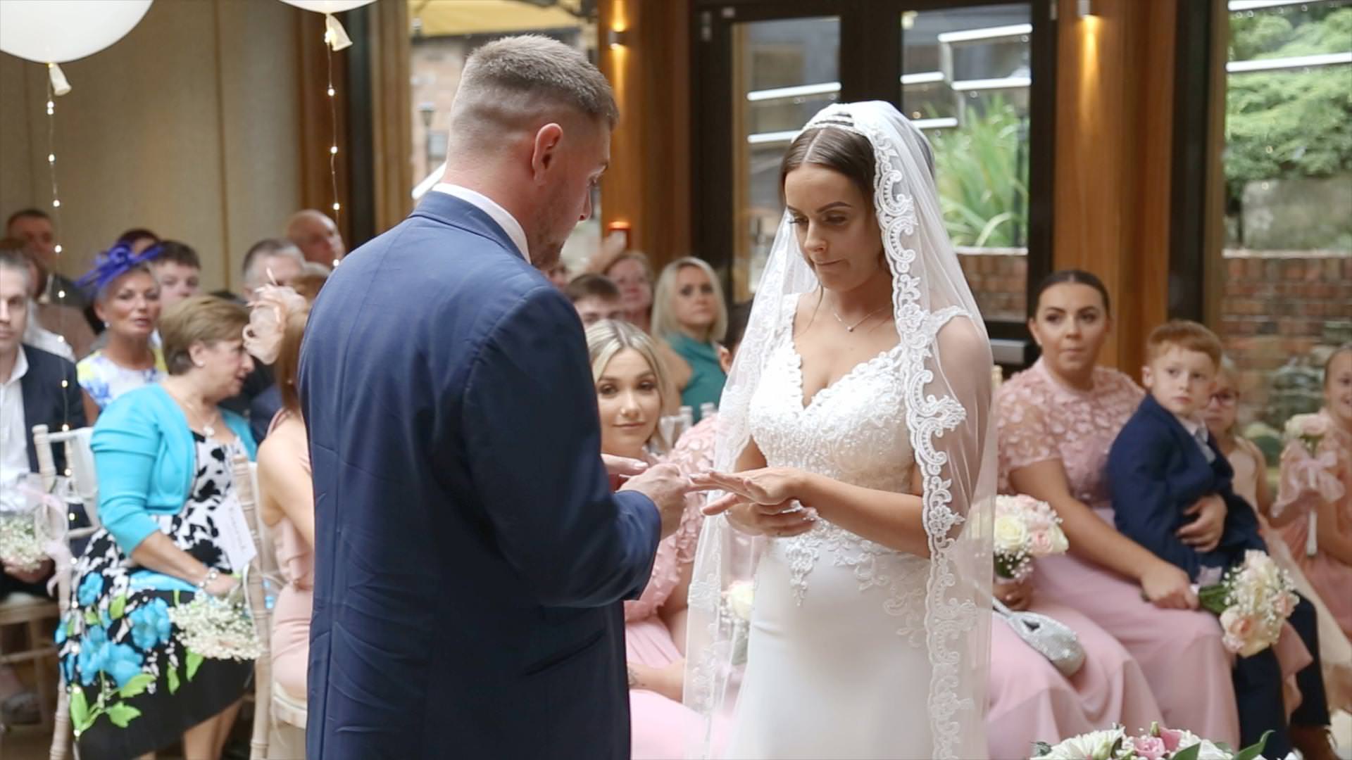 a groom puts on the brides wedding ring during their Moddershall Oaks ceremony