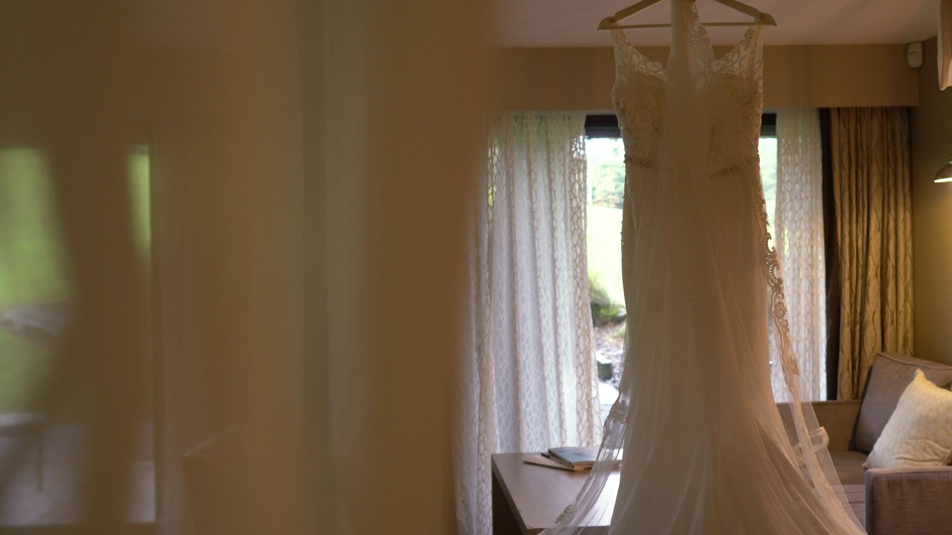 a wedding dress hangs from a four poster in a suite at Moddershall Oaks