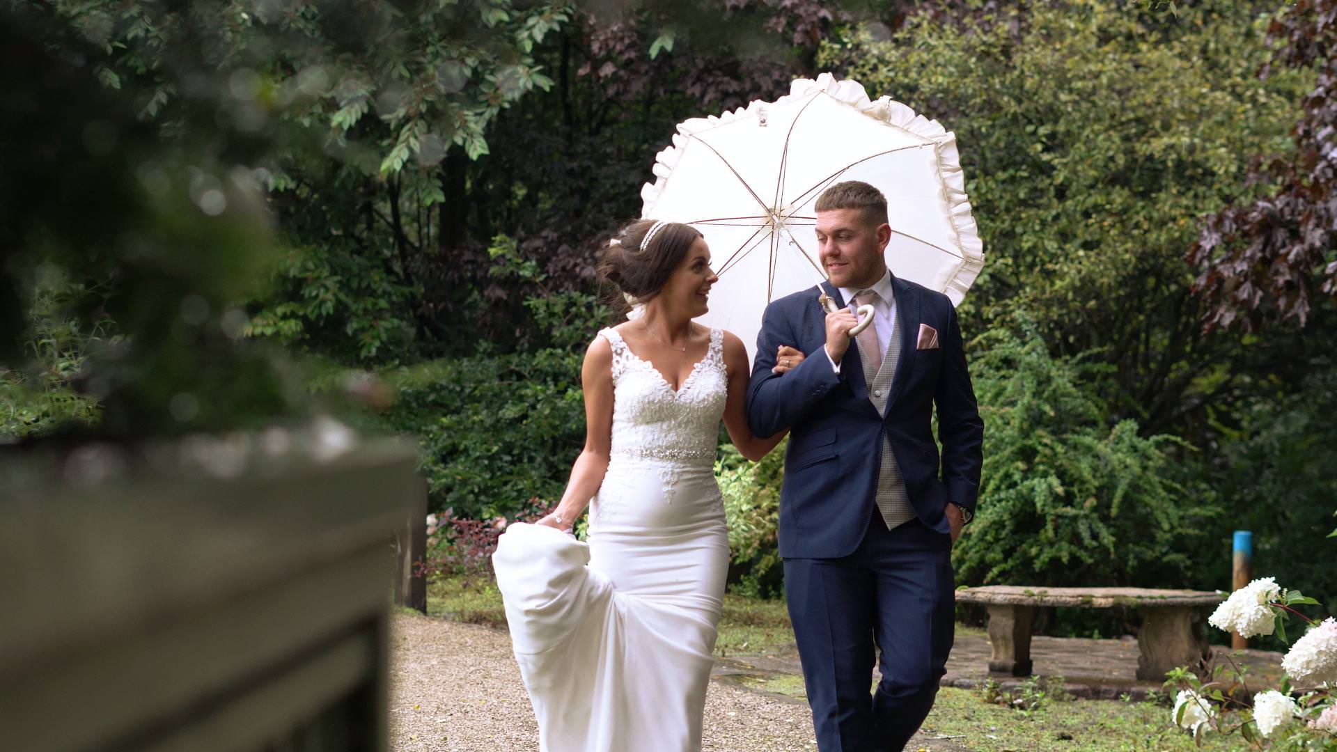 wedding videographer still of a bride and groom walking in the rain at Moddershall Oaks in Staffordshire