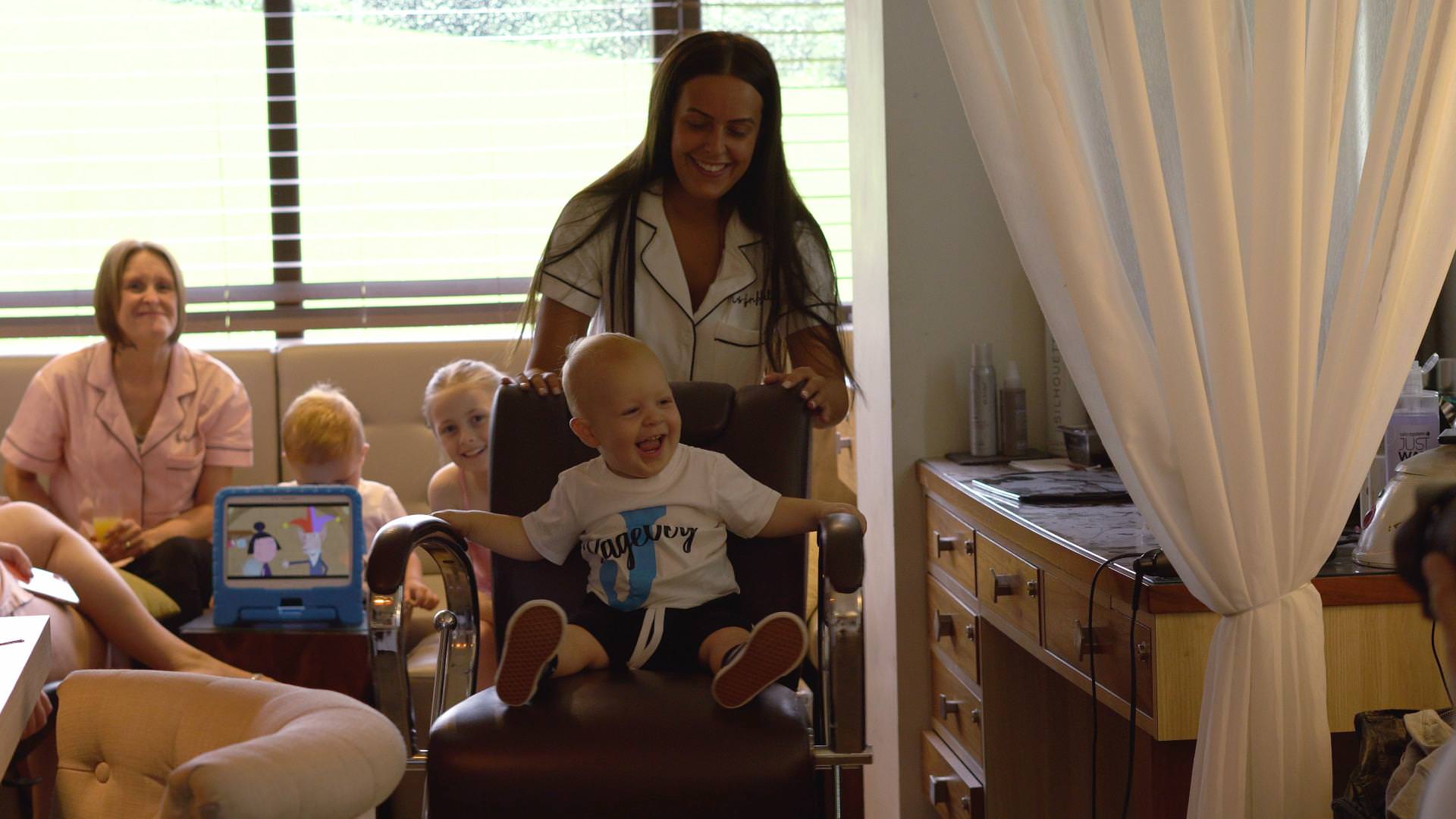 A bride spins her little boy around on a chair in the blush room at Moddershall