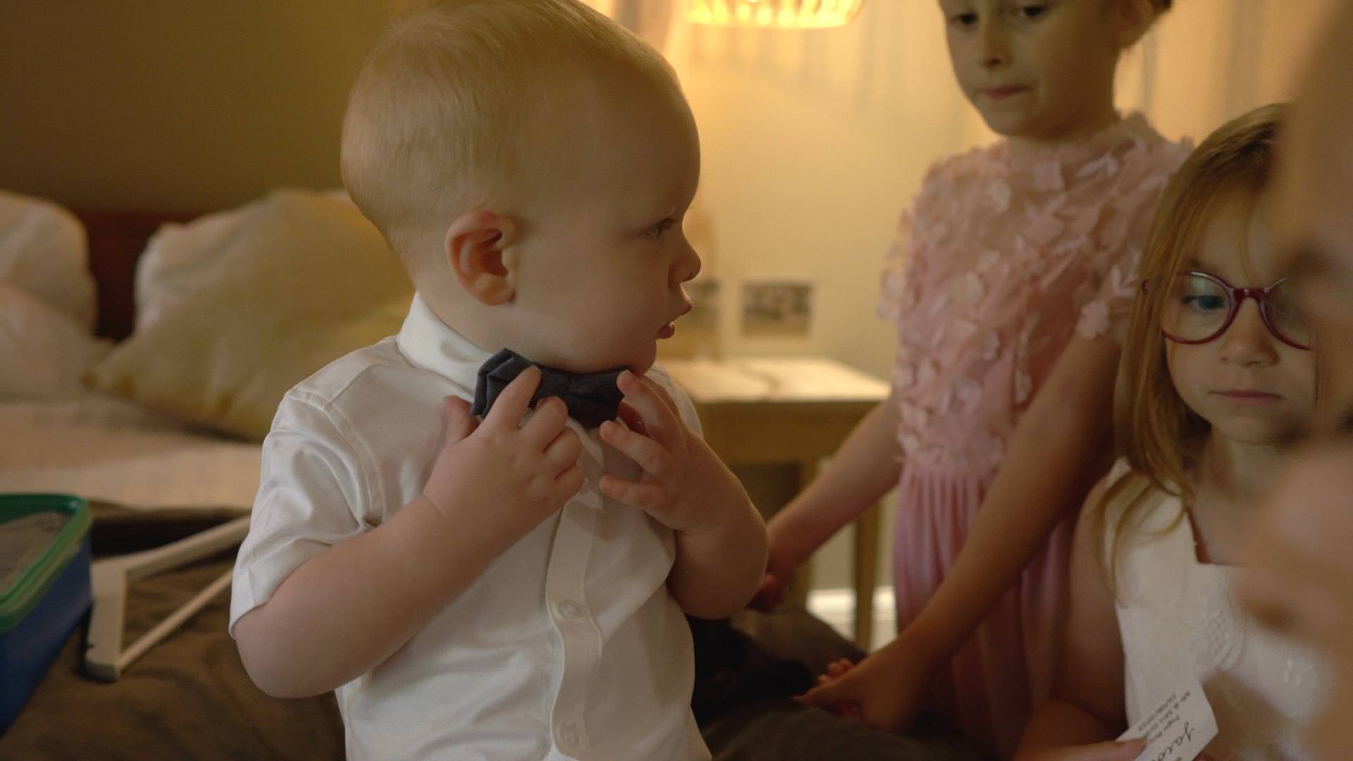 a little page boy holds his bow tie