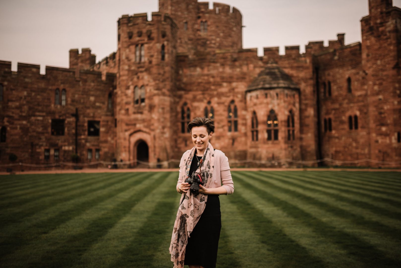 female wedding videographer holding a camera outside Peckforton Castle