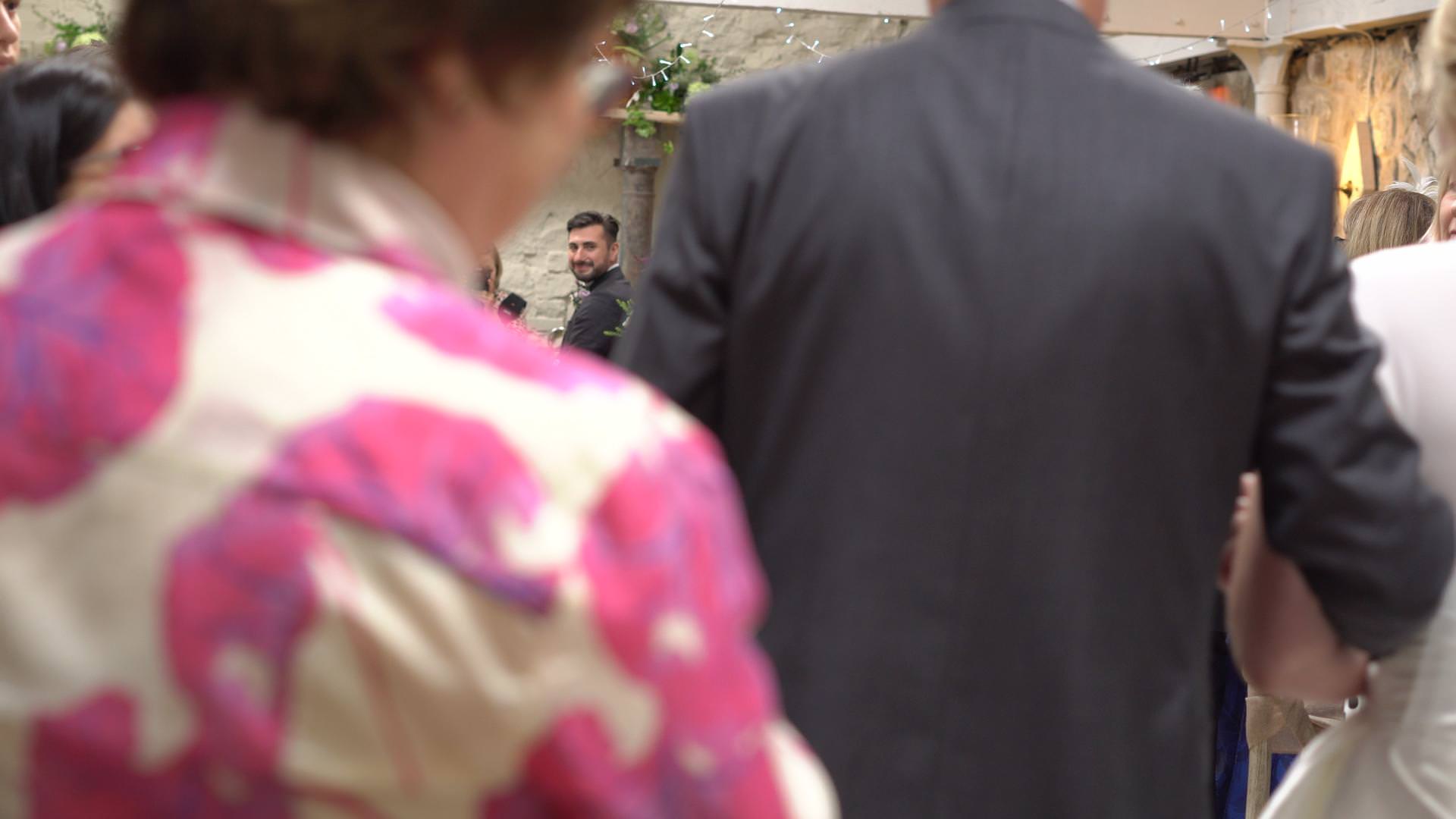 a video still of a groom turning to see his bride walk down the aisle
