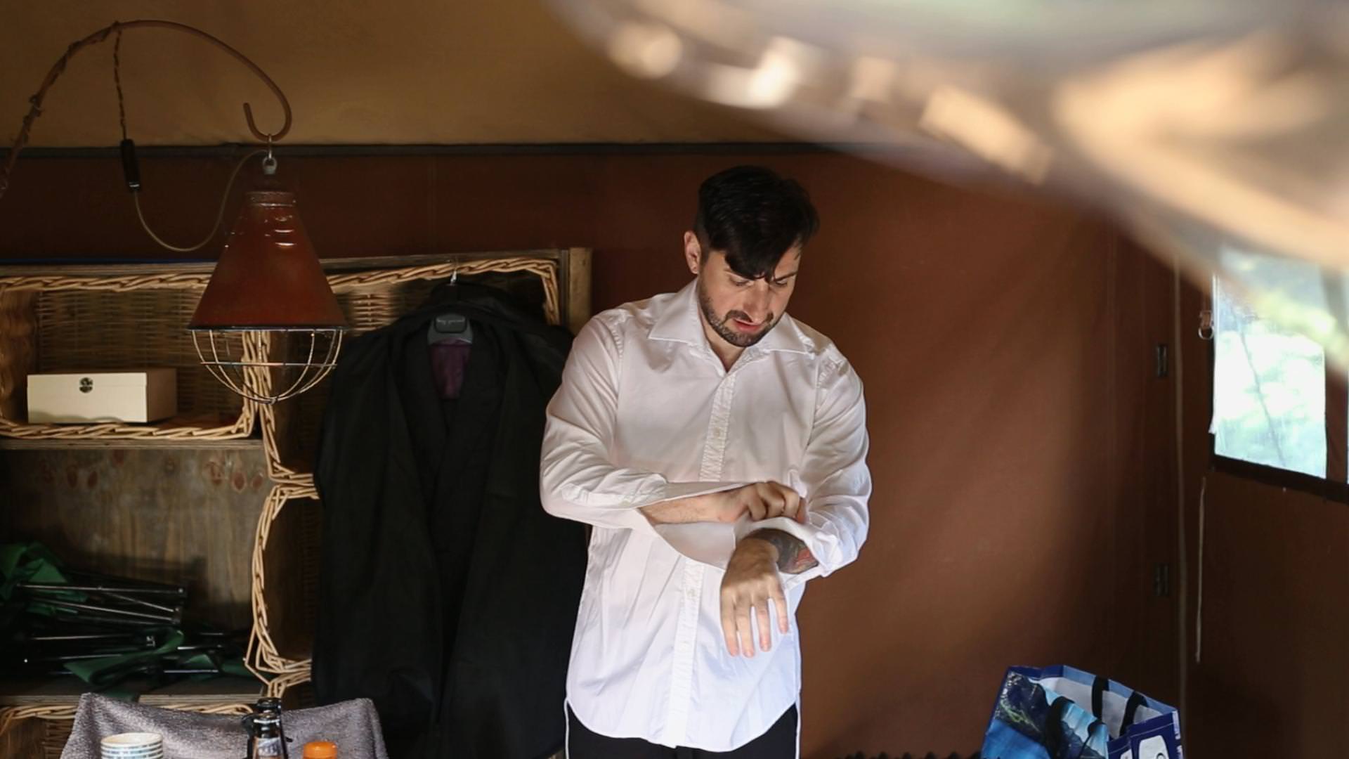 a groom putting on cufflinks in a glamping pod at wyresdale